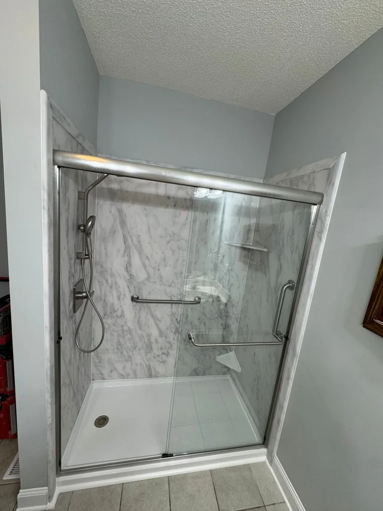 Marble-look walk-in shower with glass doors after the conversion